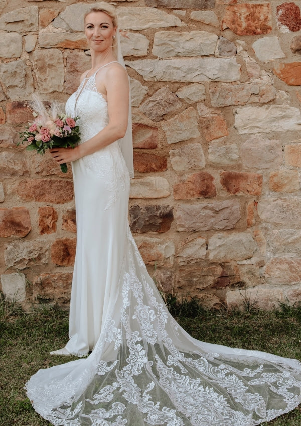 Elegante vestido de novia largo blanco de corte sirena, sin mangas, con espalda descubierta y cola, de encaje.
