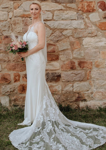 Elegante vestido de novia largo blanco de corte sirena, sin mangas, con espalda descubierta y cola, de encaje.