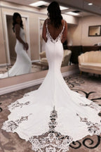 Elegante vestido de novia largo blanco de corte sirena, escote en V, tirantes finos, espalda descubierta y encaje.