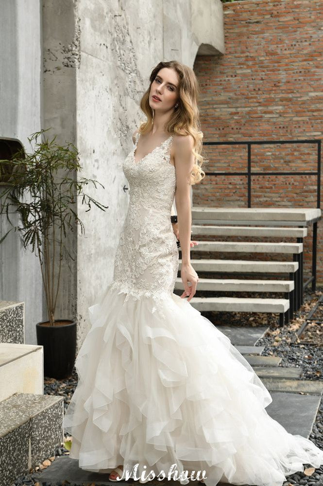 Robe de mariée sirène élégante à col en V, ornée de tulle et de dentelle, avec des appliques bouffantes.