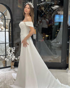 Robe de mariée en satin, coupe trapèze, épaules dénudées, ornée de perles, longueur au sol et perles de rocaille.