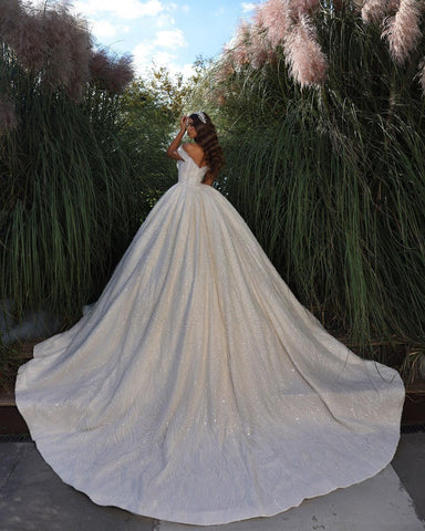 Exquisito vestido de novia largo hasta el suelo, sin mangas, con escote corazón, hombros descubiertos, corte en A, encaje y volantes.