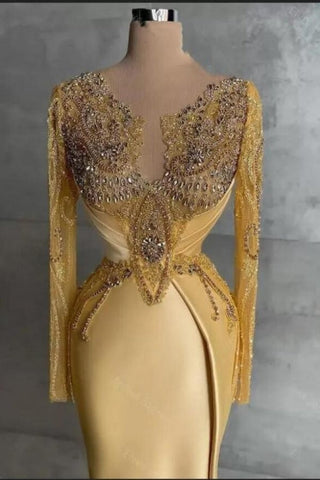 Exquisito vestido de fiesta largo de sirena dorado con encaje y pedrería, de mangas largas.