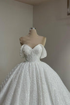 Robe de mariée extravagante blanche longue en dentelle, coupe trapèze, épaules dénudées, ornée de perles