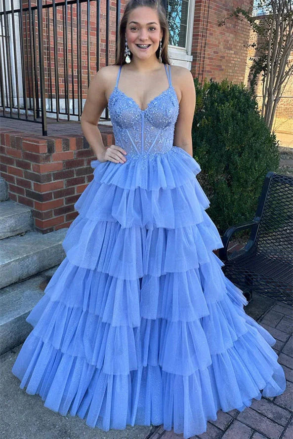 Robe de bal bleue à bretelles spaghetti, coupe trapèze, corset et appliques à volants.