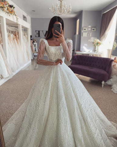 Fabuloso vestido de novia blanco de corte A, encaje, hombros descubiertos, manga larga y volantes.