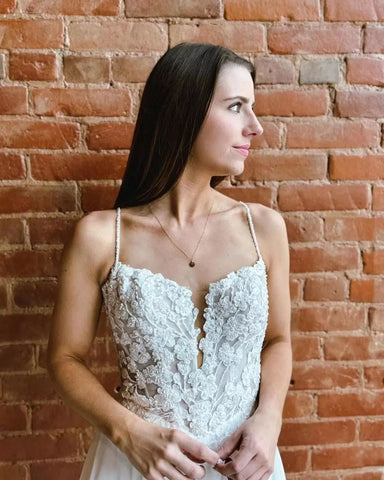 Magnifique robe de mariée blanche sans manches, coupe trapèze, bretelles spaghetti en dentelle et traîne fendue.