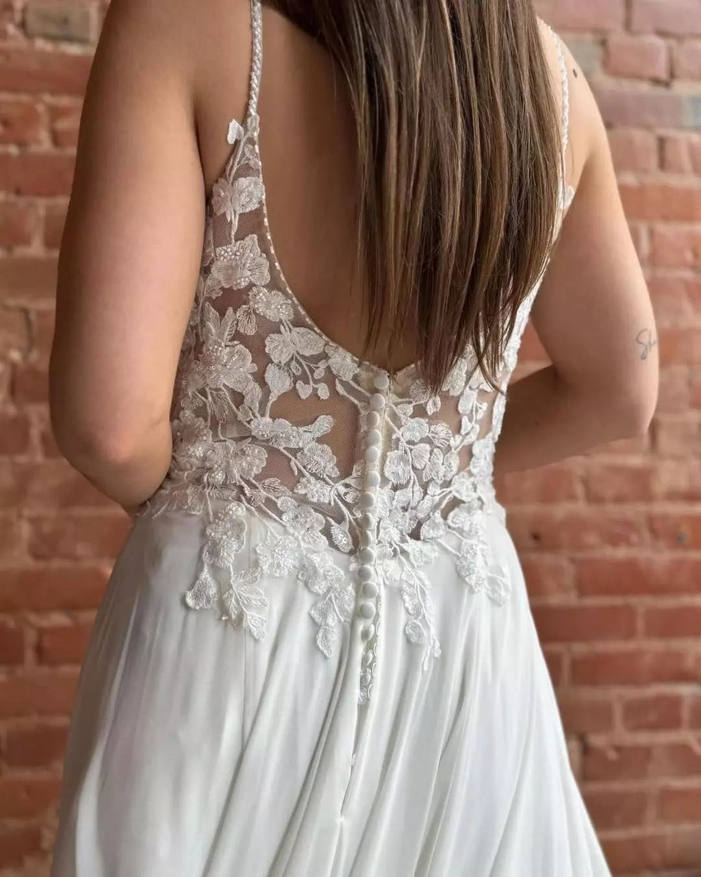 Magnifique robe de mariée blanche sans manches, coupe trapèze, bretelles spaghetti en dentelle et traîne fendue.