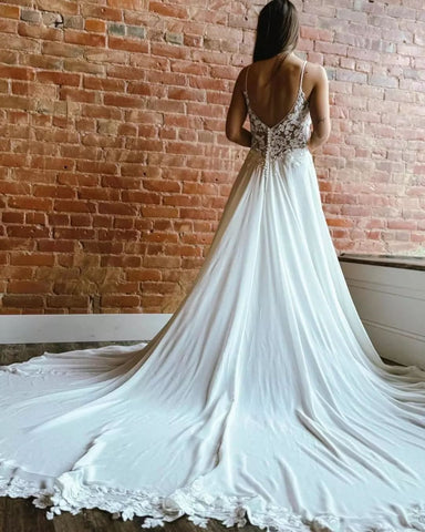 Magnifique robe de mariée blanche sans manches, coupe trapèze, bretelles spaghetti en dentelle et traîne fendue.