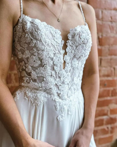 Magnifique robe de mariée blanche sans manches, coupe trapèze, bretelles spaghetti en dentelle et traîne fendue.