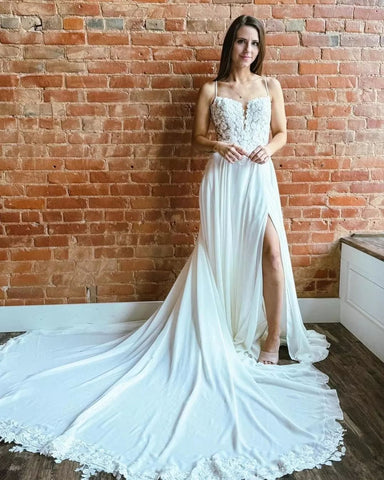 Magnifique robe de mariée blanche sans manches, coupe trapèze, bretelles spaghetti en dentelle et traîne fendue.