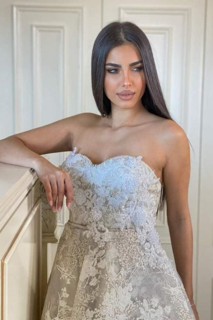Fabuleuse robe de mariée blanche en dentelle, coupe trapèze, décolleté cœur, sans manches, ornée d'appliques