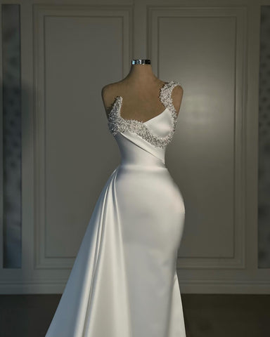 Fabuloso vestido de novia blanco de satén corte sirena, sin mangas y con un solo hombro, adornado con pedrería.