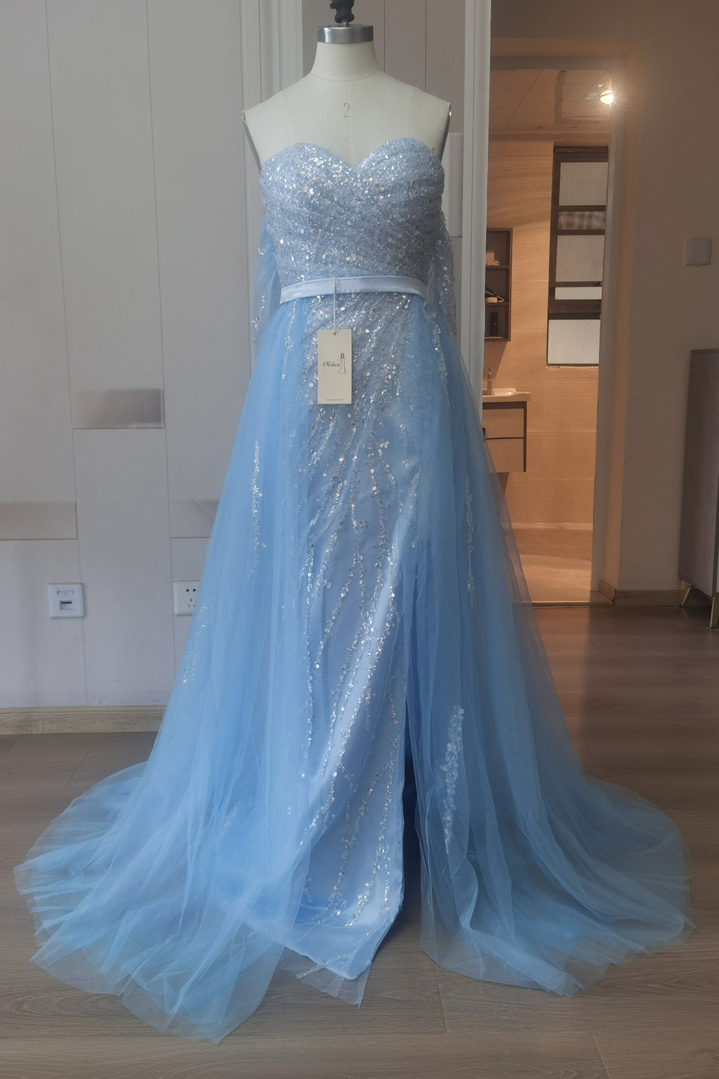 Robe de bal en tulle bleu ciel fendue sur le devant et épaules dénudées, ornée de sequins