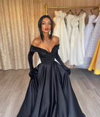 Robe de bal longue noire en satin, coupe trapèze, épaules dénudées, avec gants.