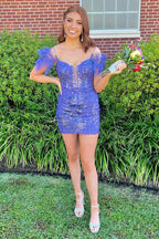 Vestido corto de fiesta estilo vainica con hombros descubiertos, lentejuelas azul galaxia y plumas.