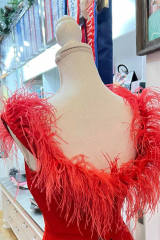 Vestido largo de gala rojo con escote pronunciado y detalles de plumas, con abertura.