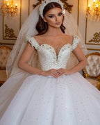 Robe de mariée longue princesse glamour à épaules dénudées, ornée de perles et de tulle, style perle et perles.