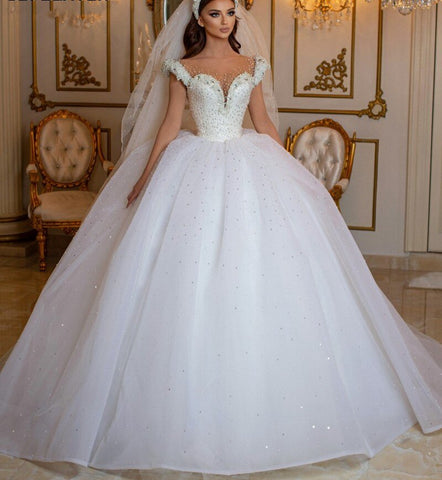 Robe de mariée longue princesse glamour à épaules dénudées, ornée de perles et de tulle, style perle et perles.