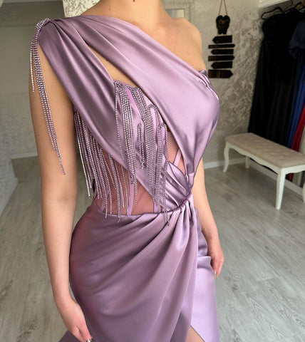 Elegante vestido largo de fiesta morado con un solo hombro, bordado con cuentas, sin mangas y abertura larga. Disponible en línea.