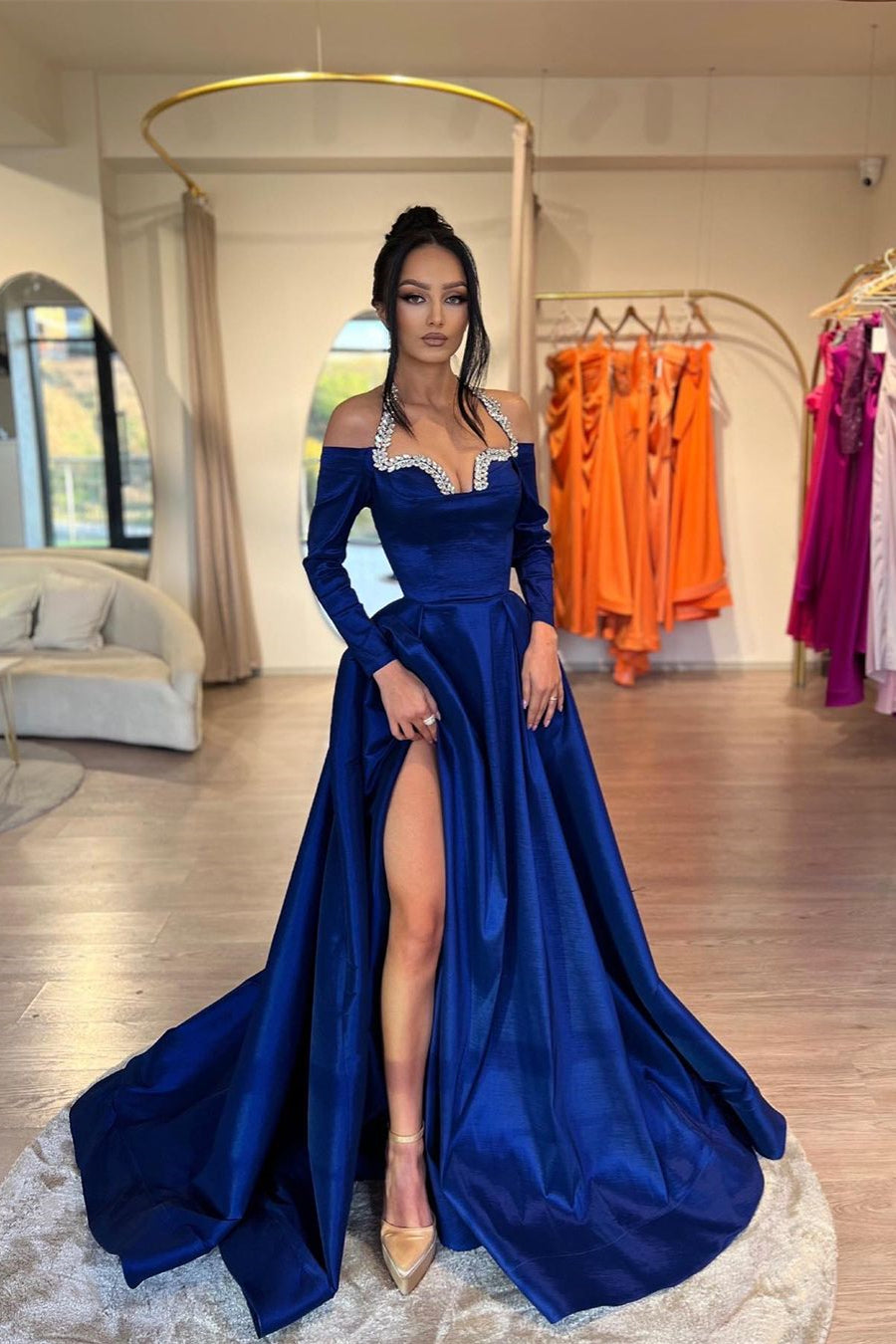 Elegante vestido de fiesta largo azul real, corte en A, escote halter, mangas largas, pedrería y abertura.
