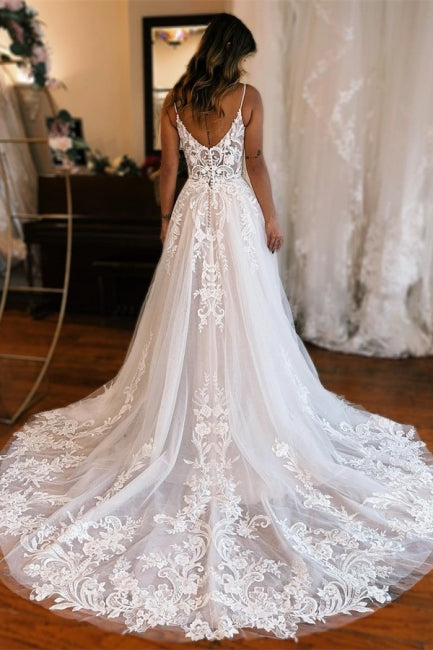 Robe de mariée longue blanche glamour, coupe trapèze, bretelles spaghetti, sans manches, en dentelle et fendue.