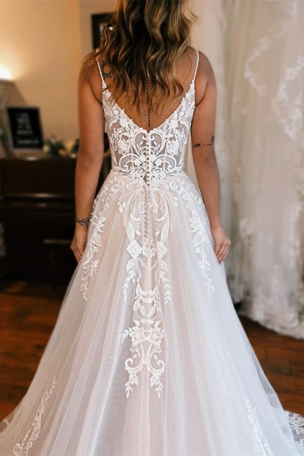 Robe de mariée longue blanche glamour, coupe trapèze, bretelles spaghetti, sans manches, en dentelle et fendue.