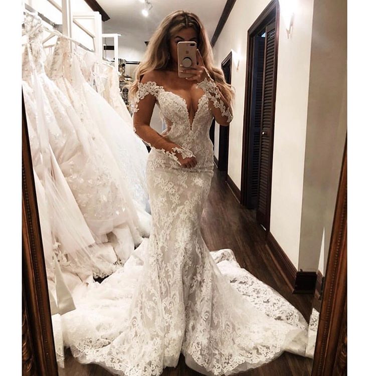 Vestido de novia sirena glamuroso con hombros descubiertos, mangas largas, escote en V y apliques.