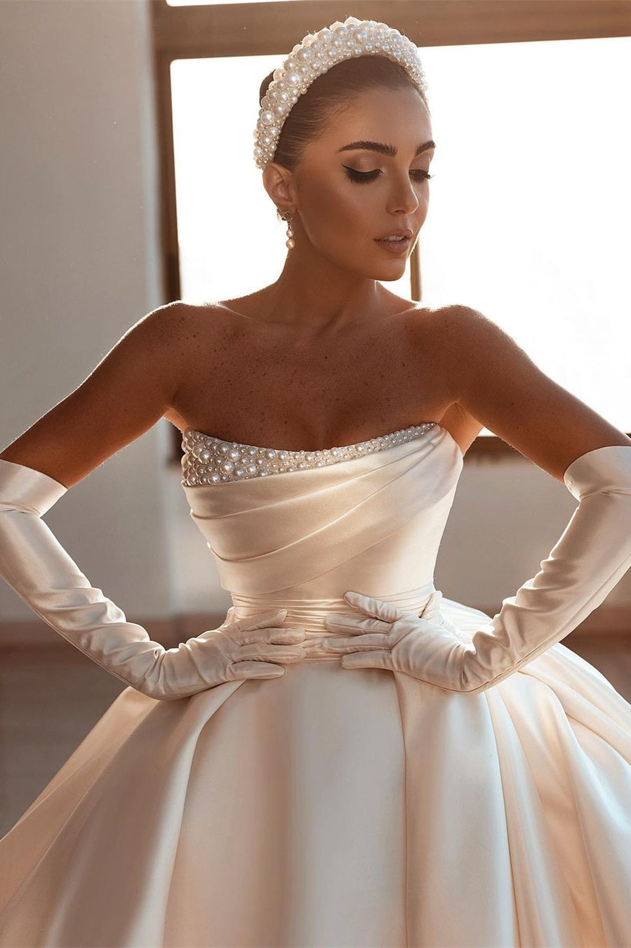 Robe de mariée glamour en satin blanc, coupe trapèze, ornée de perles et avec traîne