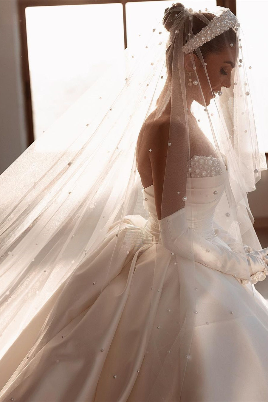 Robe de mariée glamour en satin blanc, coupe trapèze, ornée de perles et avec traîne