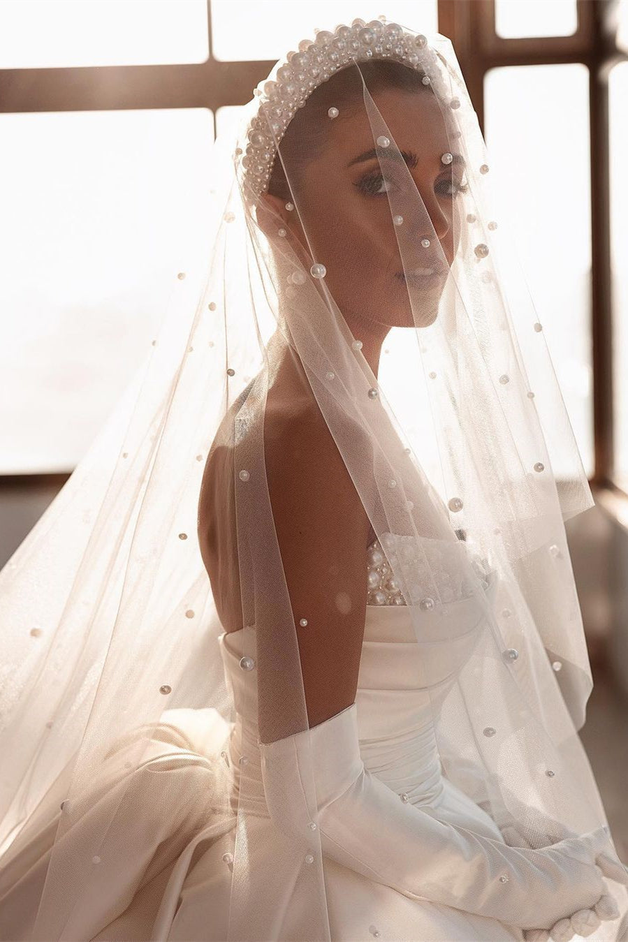 Robe de mariée glamour en satin blanc, coupe trapèze, ornée de perles et avec traîne