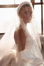 Robe de mariée glamour en satin blanc, coupe trapèze, ornée de perles et avec traîne