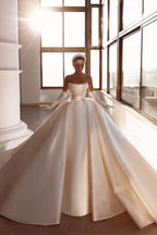 Robe de mariée glamour en satin blanc, coupe trapèze, ornée de perles et avec traîne