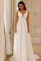 Magnifique robe de mariée blanche en mousseline de soie et dentelle, coupe trapèze, col en V, sans manches et dos nu.