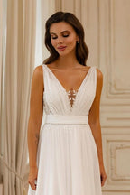 Magnifique robe de mariée blanche en mousseline de soie et dentelle, coupe trapèze, col en V, sans manches et dos nu.
