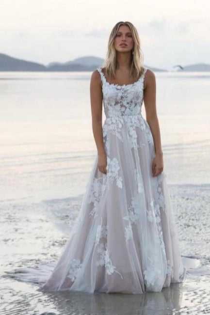 Magnifique robe de mariée blanche en dentelle, coupe trapèze, décolleté rond, sans manches, ornée d'appliqués et d'une traîne.
