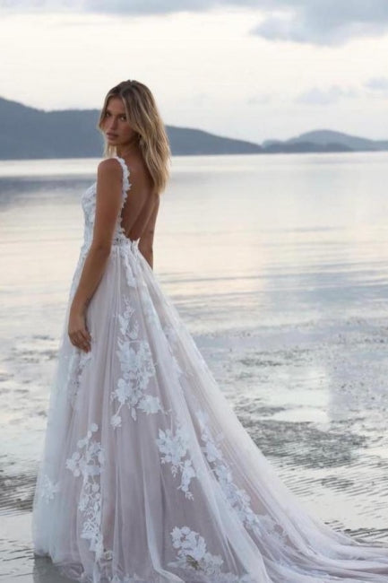 Magnifique robe de mariée blanche en dentelle, coupe trapèze, décolleté rond, sans manches, ornée d'appliqués et d'une traîne.