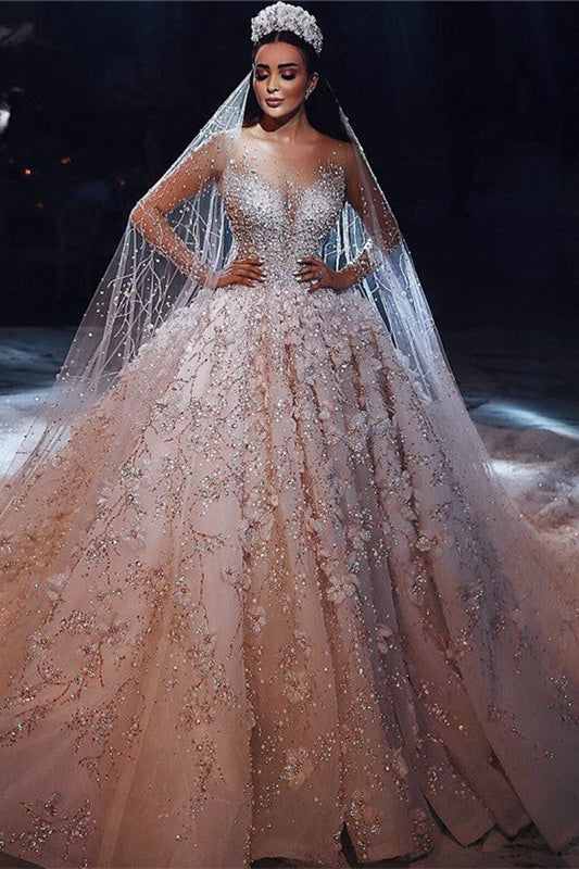 Magnifique robe de mariée princesse à manches longues et col transparent, ornée de perles et de fleurs.