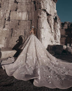 Magnifique robe de mariée princesse à manches longues et col transparent, ornée de perles et de fleurs.