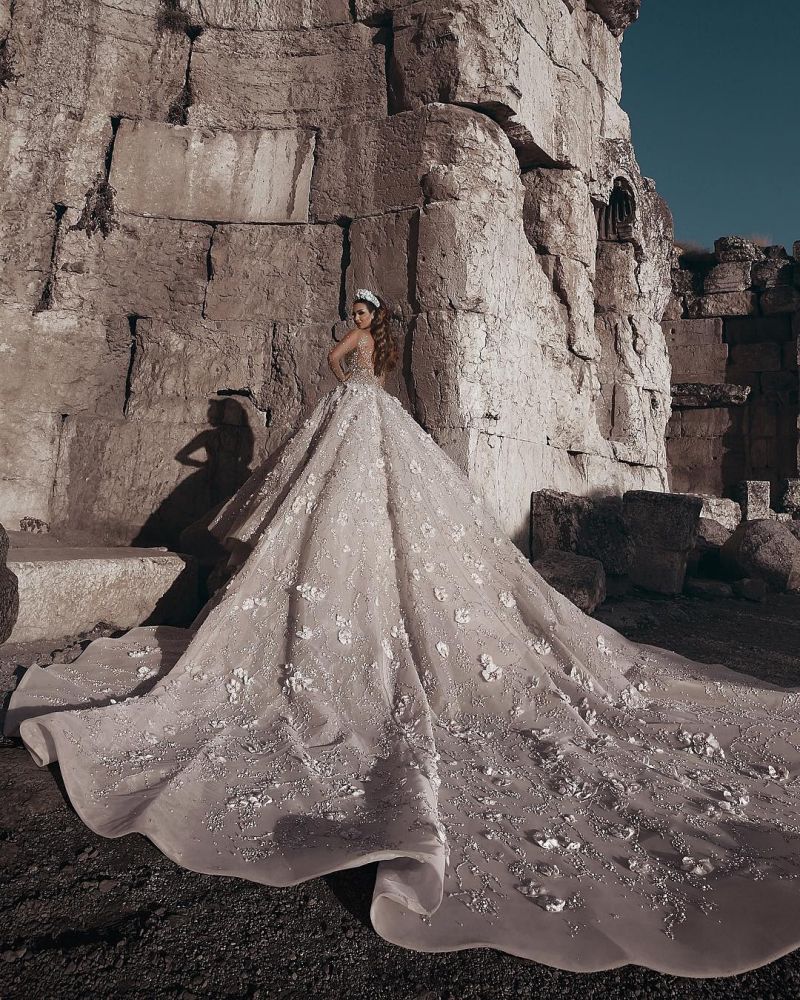 Magnifique robe de mariée princesse à manches longues et col transparent, ornée de perles et de fleurs.