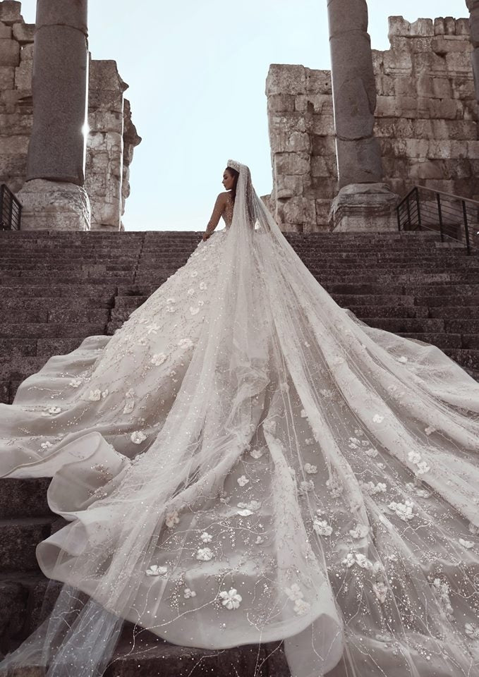 Magnifique robe de mariée princesse à manches longues et col transparent, ornée de perles et de fleurs.