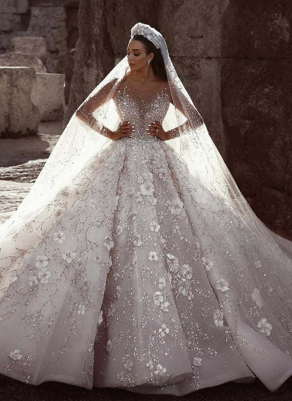 Magnifique robe de mariée princesse à manches longues et col transparent, ornée de perles et de fleurs.