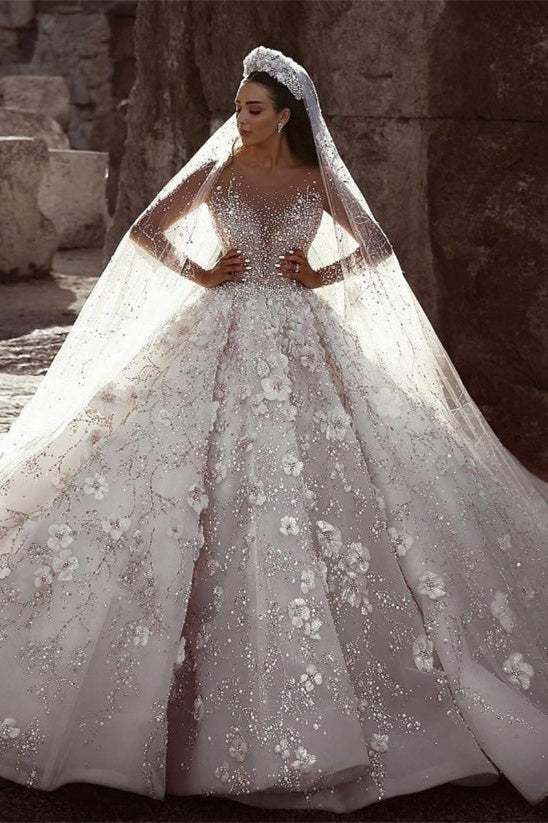 Magnifique robe de mariée princesse à manches longues et col transparent, ornée de perles et de fleurs.