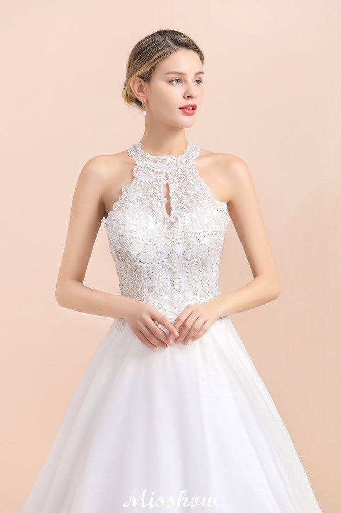 Magnifique robe de mariée dos nu ornée de strass, en tulle blanc et dentelle appliquée, coupe trapèze.