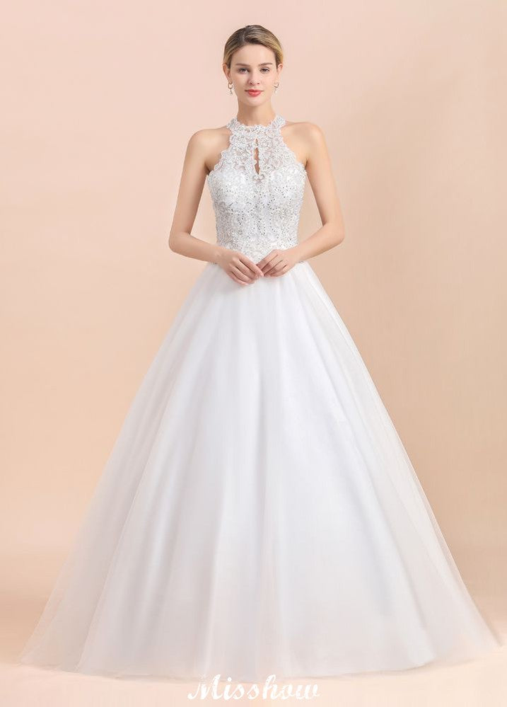 Magnifique robe de mariée dos nu ornée de strass, en tulle blanc et dentelle appliquée, coupe trapèze.