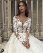 Precioso vestido de novia largo de corte A con escote barco, apliques, cola de encaje y mangas, con mangas y apliques.