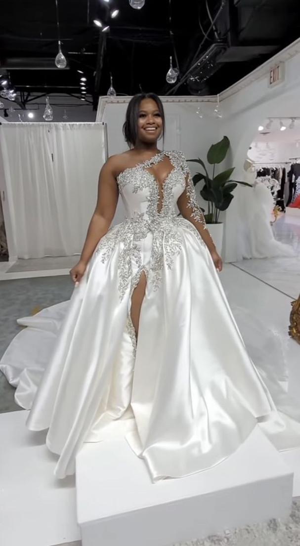 Magnifique robe de mariée longue trapèze asymétrique à une épaule, ornée de perles et fendue.