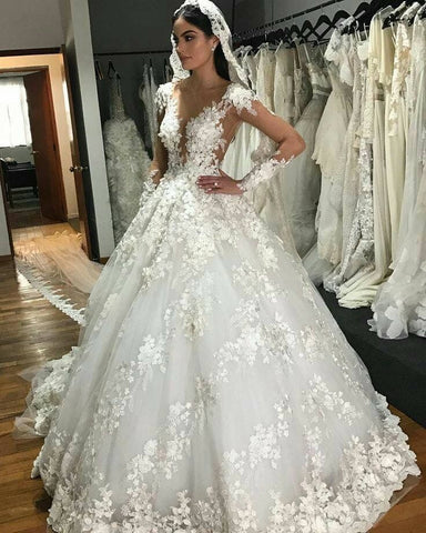 Precioso vestido de novia largo estilo princesa con escote barco, apliques de encaje, espalda descubierta, volantes y mangas.