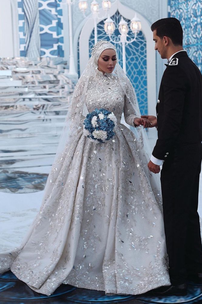 Robe de mariée somptueuse à sequins, manches longues, col montant et traîne.