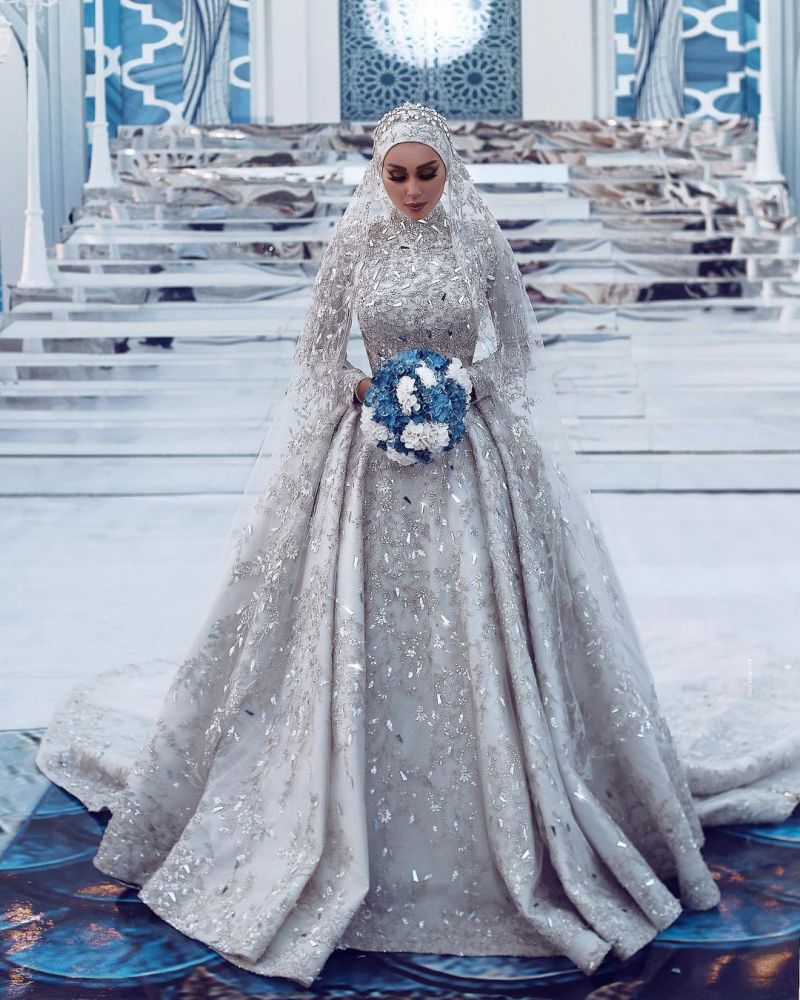 Robe de mariée somptueuse à sequins, manches longues, col montant et traîne.